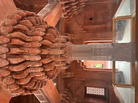       Intricately carved central pillar with elaborate stone brackets inside Fatehpur Sikri's Diwan-i-Khas.
  
