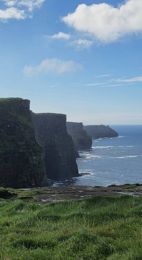       Dramatic vertical sea cliffs rise above the Atlantic Ocean with waves crashing at their base at the Cliffs of Moher.
  