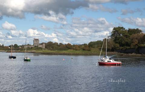       Small sailboats anchored on a calm estuary with a distant castle and signature watermark in the corner.
  