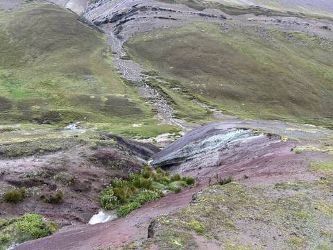       Close view of multicolored earth and small ravines on a high Andean slope.
  