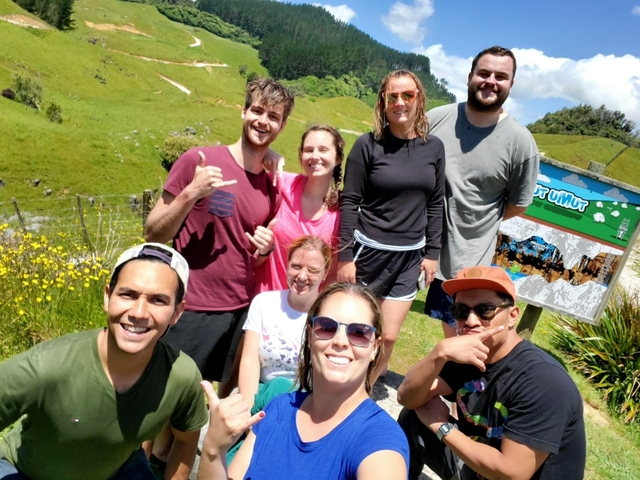 Group of friends posing outdoors with hills in the background.