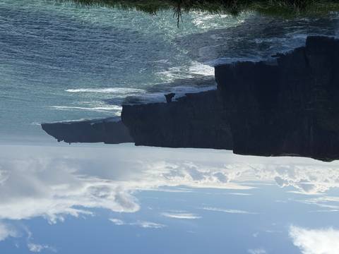       Dramatic sea cliffs of the Cliffs of Moher rising vertically above the Atlantic waves.
  