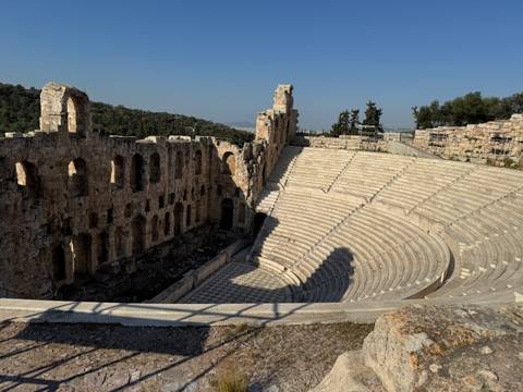       Stone tiers of the Odeon of Herodes Atticus amphitheatre curve gracefully beneath clear skies.
  