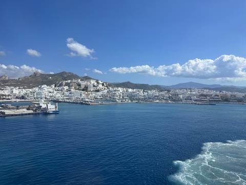       Panoramic coastal town with whitewashed buildings hugging the shoreline of deep blue sea.
  