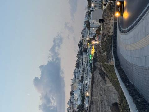       Winding cliff-top road overlooking Santorini’s villages as evening light fades.
  
