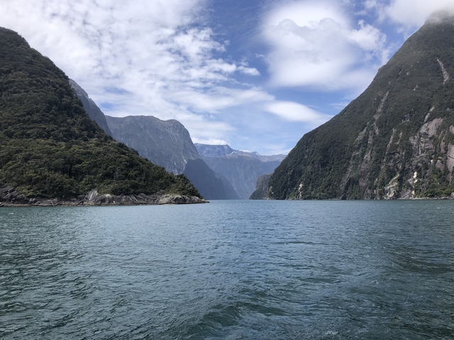 Fjord landscape with steep cliffs and a blue sky.