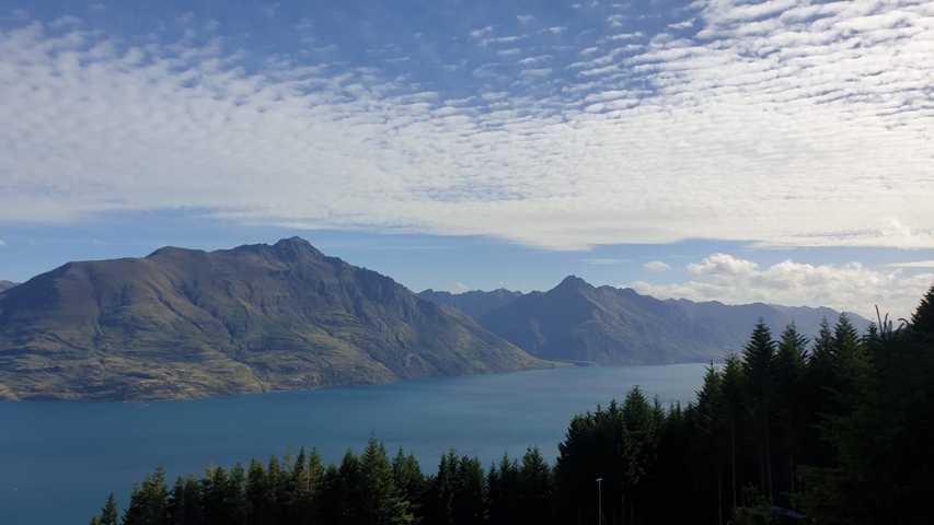 Panoramic view of mountains and a lake under a blue sky.