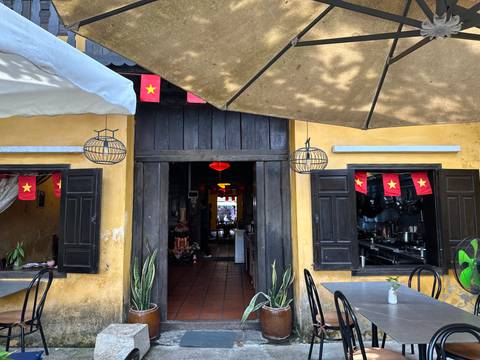       Yellow-washed café façade decorated with Vietnamese flags and traditional lanterns.
  