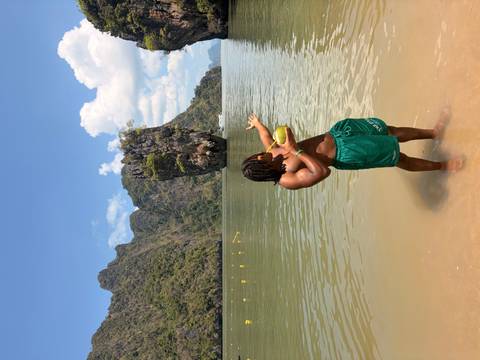       Traveller sips a coconut while pointing toward the famous limestone spike in the bay.
  
