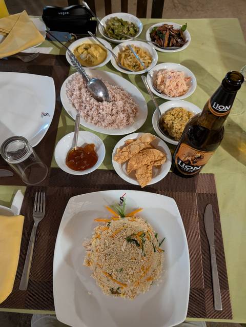       Traditional Sri Lankan meal with rice, curry, papad and Lion beer on a restaurant table
  