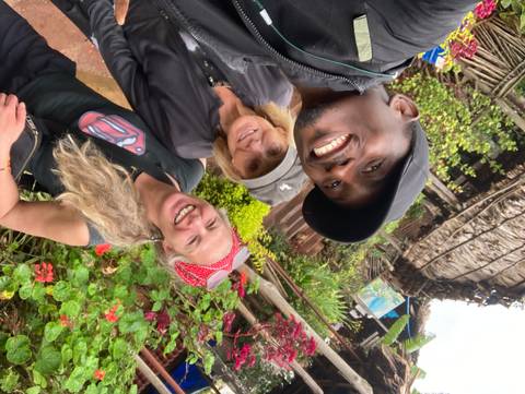      Happy selfie of guide and two travellers amid lush village garden
  