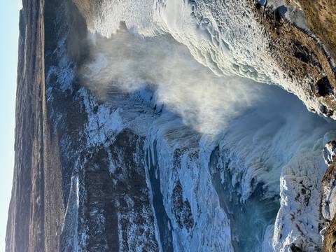       Powerful spray rising from a partially frozen waterfall plunging into a deep chasm at Gullfoss.
  
