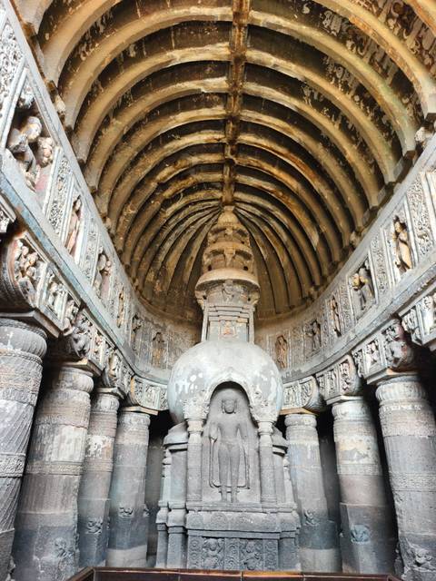       Interior of an ancient chaitya hall with a ribbed stone ceiling and central stupa at Ajanta.
  