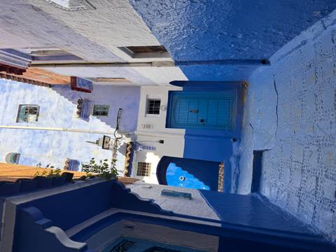       Narrow alleyway of vivid blue-painted houses and carved doors in Chefchaouen’s medina.
  