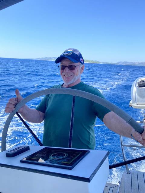 Man steering a boat with a vast ocean view.