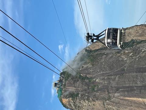       Iconic Sugarloaf cable car gliding past a granite peak with blue sky over Rio de Janeiro.
  