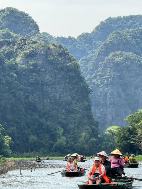       Dramatic green karst cliffs rising above a verdant valley under soft light.
  
