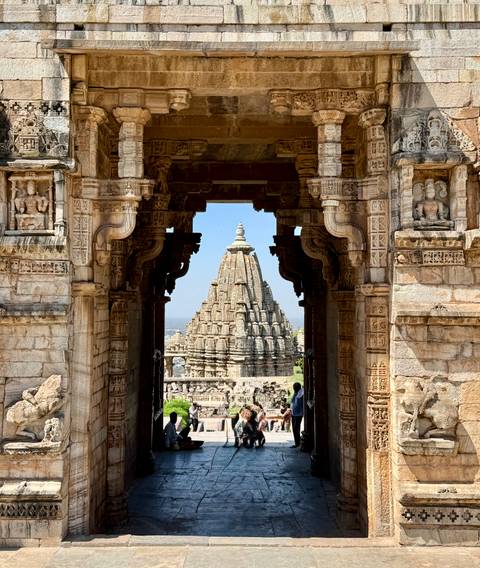       Stone gateway framing a soaring temple tower at an ancient hilltop fort complex.
  