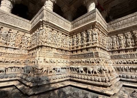       Elaborately carved stone panels depicting deities, dancers and animals on a temple wall.
  