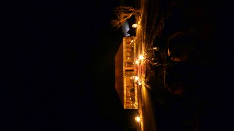       Distant desert camp tent illuminated by lanterns against dark night sky.
  