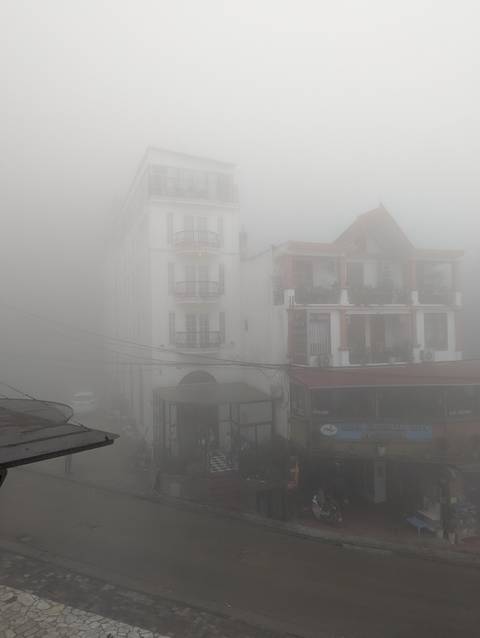       Tall white hotel facade barely visible through dense mountain fog
  