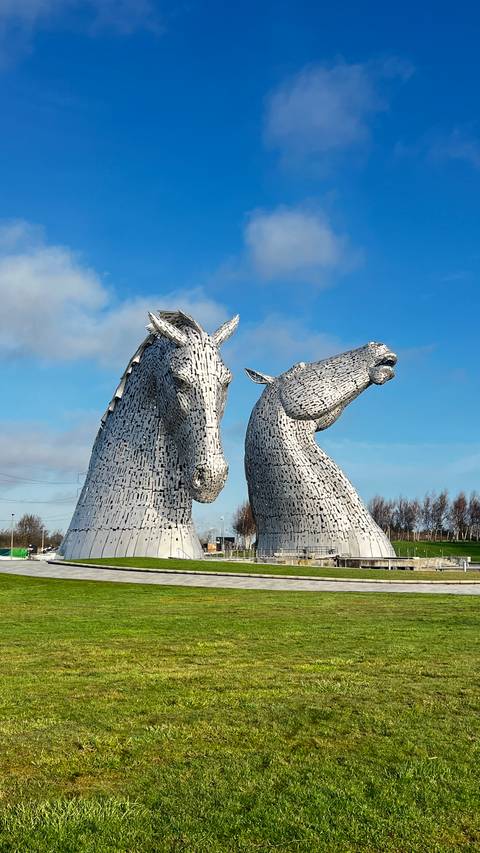       The giant steel horse-head sculptures known as The Kelpies gleam under a clear blue Scottish sky.
  
