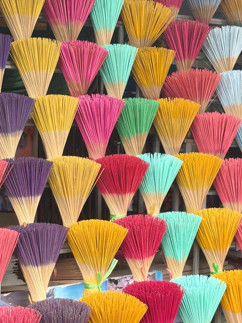       Colorful bundles of incense sticks neatly arranged in rows creating a vibrant pattern
  