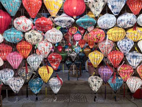       Display of colorful handcrafted lanterns hanging in rows at a Vietnamese market stall
  