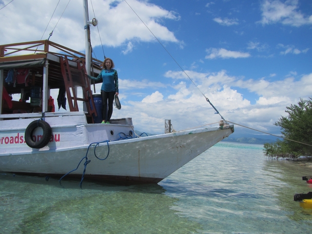       Woman standing on a boat in a scenic coastal area.
  