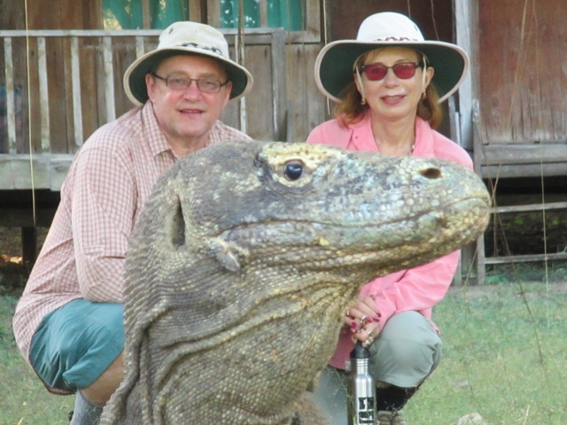       Two people posing with a Komodo dragon.
  