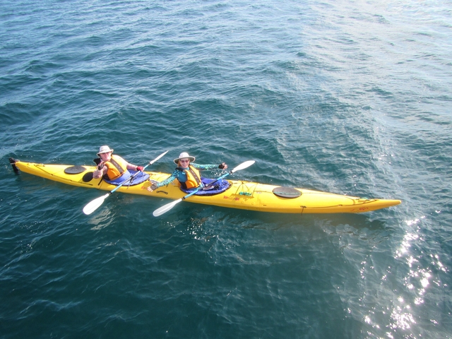       Two people kayaking in a yellow kayak on the water.
  