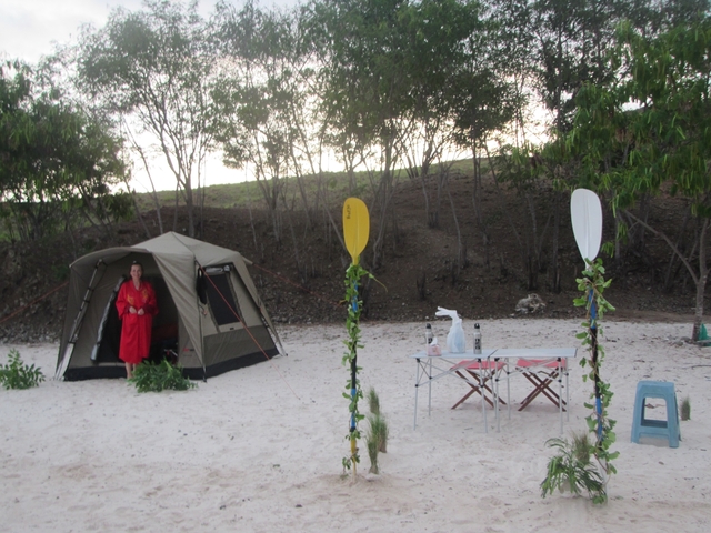       Tent set up on a beach with camping equipment.
  