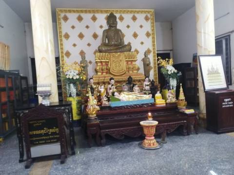       Slightly blurry interior shrine with seated Buddha and decorative offerings
  