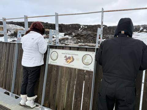       Travellers read an information board at the Bridge Between Continents on a bleak, snowy landscape.
  