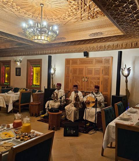       Traditional Moroccan musicians performing in a decorated dining room.
  