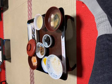       Traditional Japanese breakfast tray with rice, soup, tea and small side dishes on tatami mat.
  