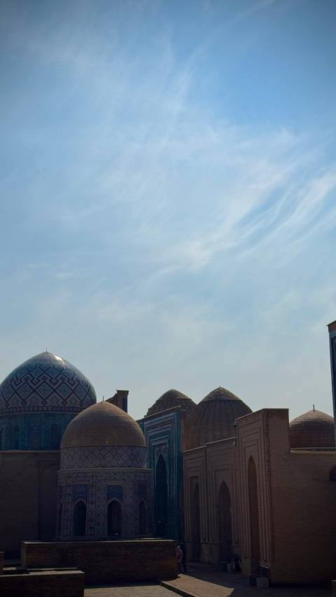       The patterned dome of an Islamic building peeks into an otherwise empty, bright blue sky.
  