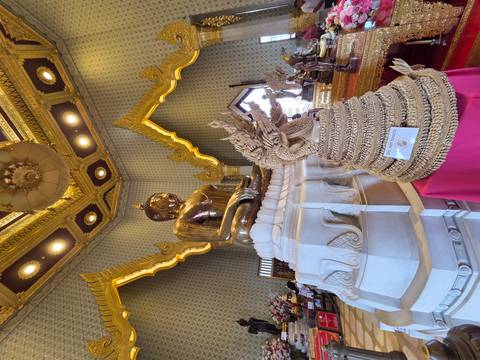       Polished golden Buddha inside ornate temple hall with intricate patterned walls and decorative ceiling
  