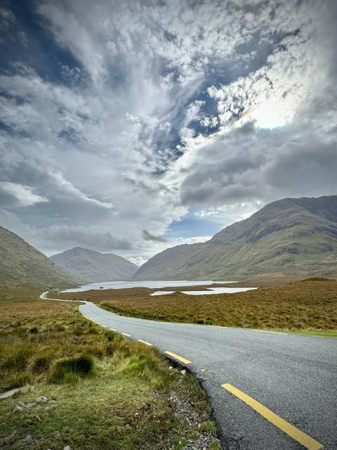       Serene mountain lake nestled between misty green peaks under a dramatic cloudy sky
  