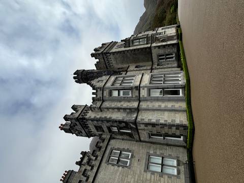       Grey stone castle-like mansion with crenellations set against a misty Irish sky
  