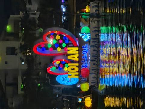       Illuminated floating heart and lantern display spelling HOI AN glowing on the river at night
  