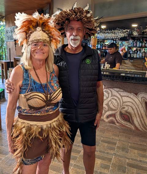       Traveler posing with a local woman in traditional costume inside a café or bar on Easter Island.
  