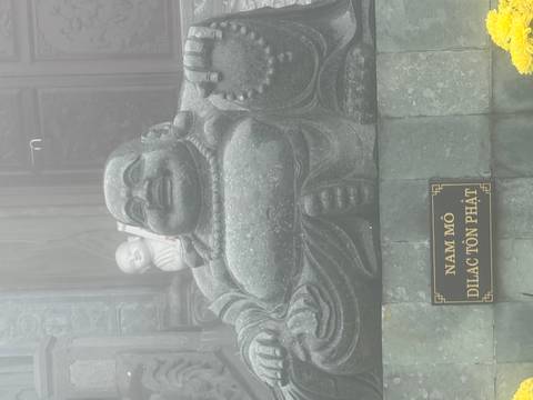       Large stone laughing Buddha statue partially shrouded in mist at a mountaintop temple.
  