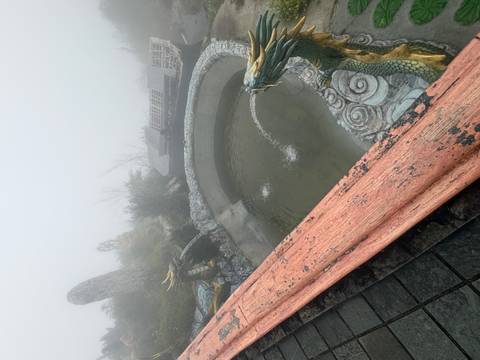       Foggy terrace with dragon fountains spilling water into a stone pool.
  