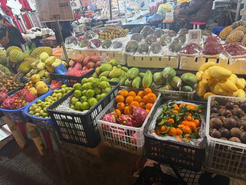       Abundant tropical fruits arranged in colorful baskets at an indoor market.
  
