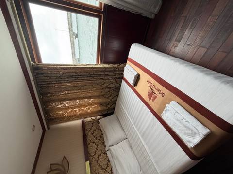       Cozy cabin room with double bed, embroidered runner and window view of harbour.
  