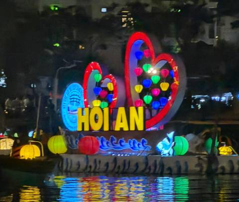       Colorful illuminated 'HOI AN' sign with bright multicolored lanterns against the night sky.
  