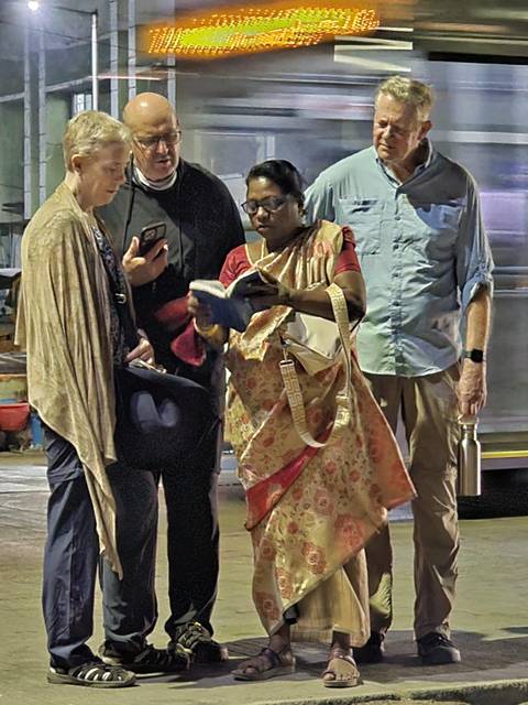       Low-light scene of travellers consulting a guidebook beside luggage on a station platform.
  