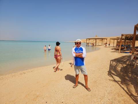       Tourists relax on a quiet Red Sea beach with calm turquoise water and straw shelters
  