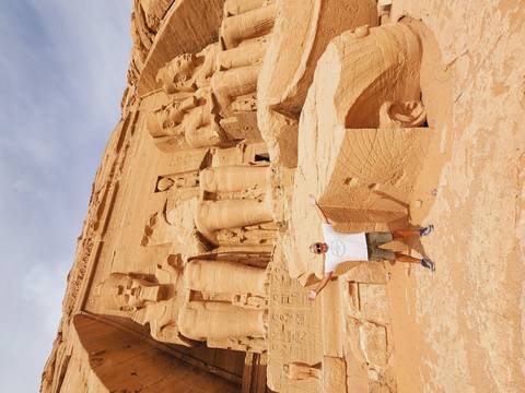       Visitor spreads arms joyfully before the colossal statues of Abu Simbel temple
  